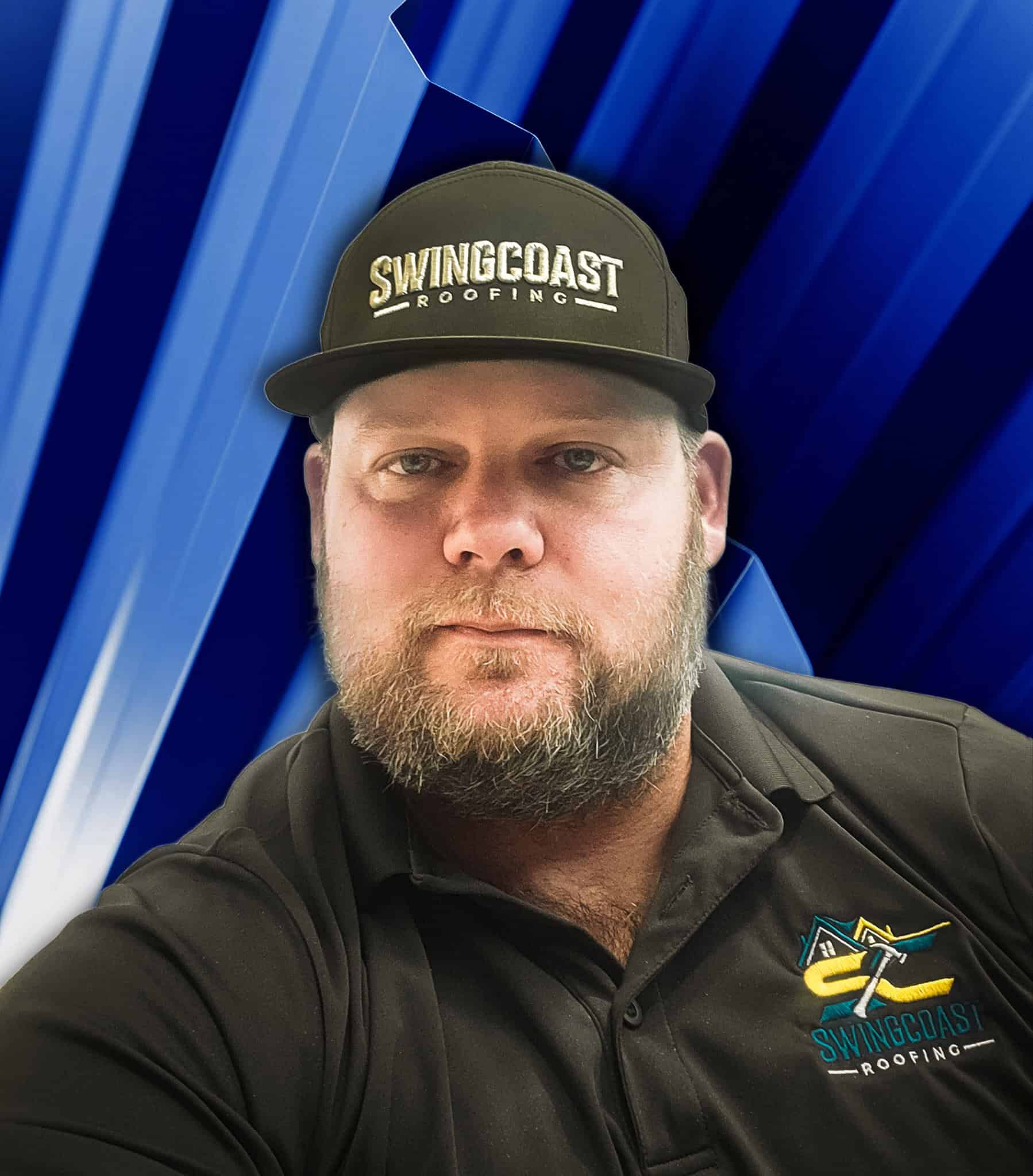 Portrait of a SwingCoast Roofing team member wearing a black SwingCoast Roofing hat and black company polo shirt, posed against a blue metal roofing background.